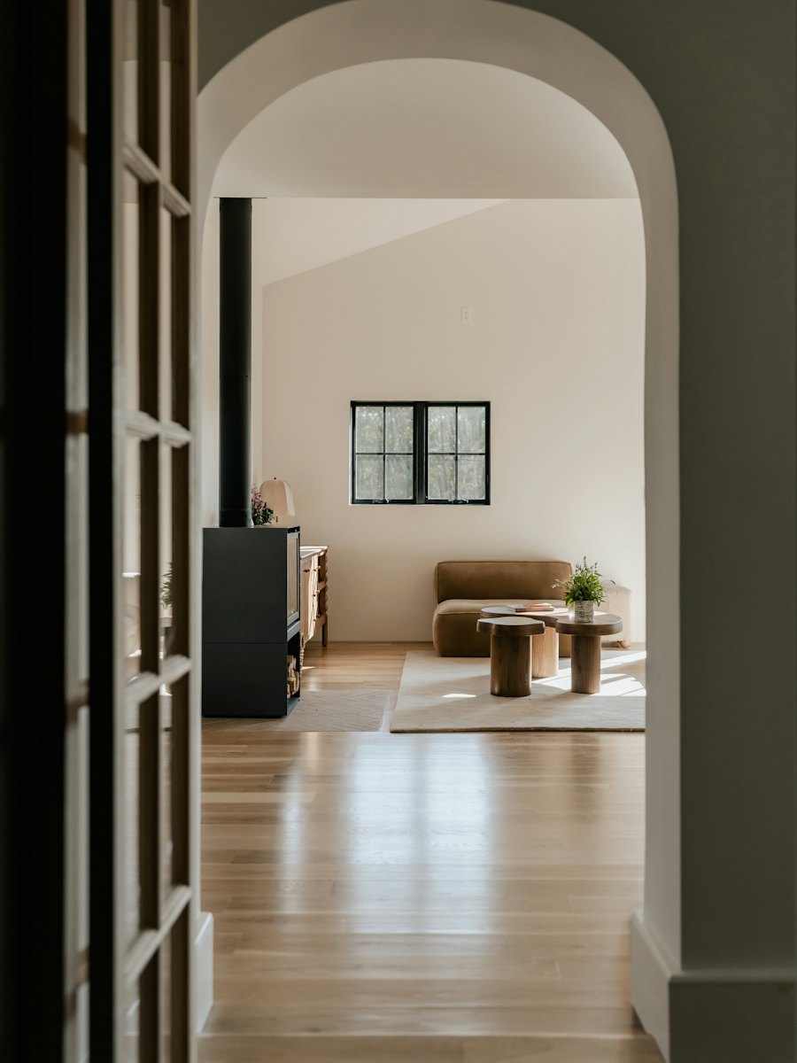 An arched hallway with wood floors leading into a tidy living and dining room